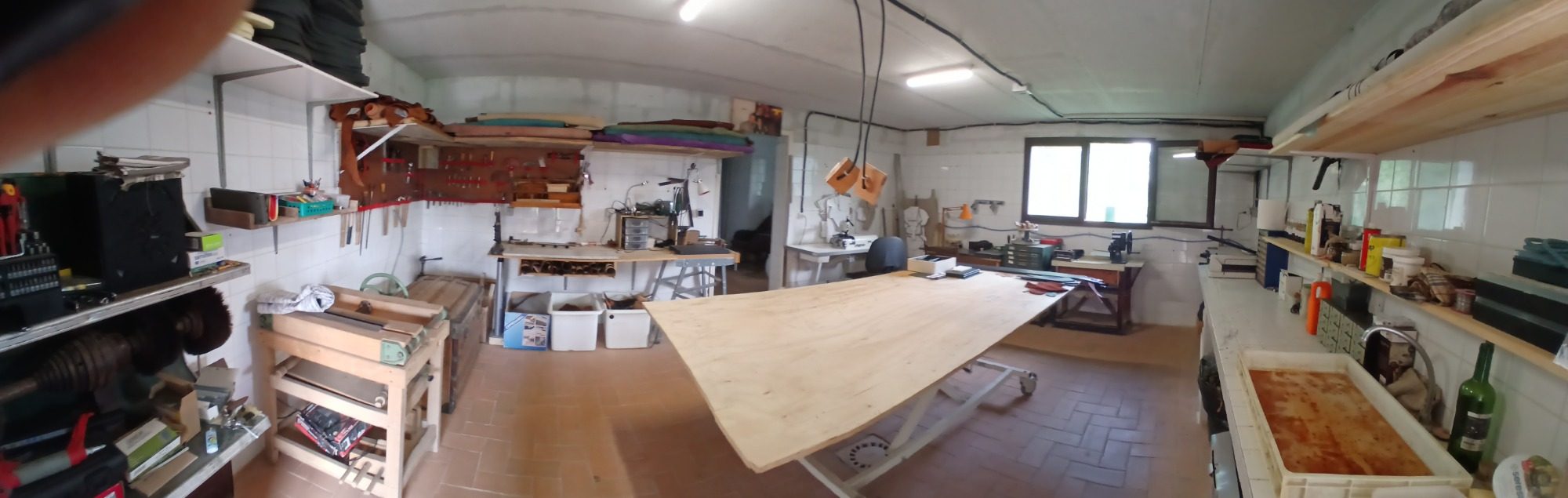 Atelier d'art bien organisé avec une grande table en bois et divers outils.